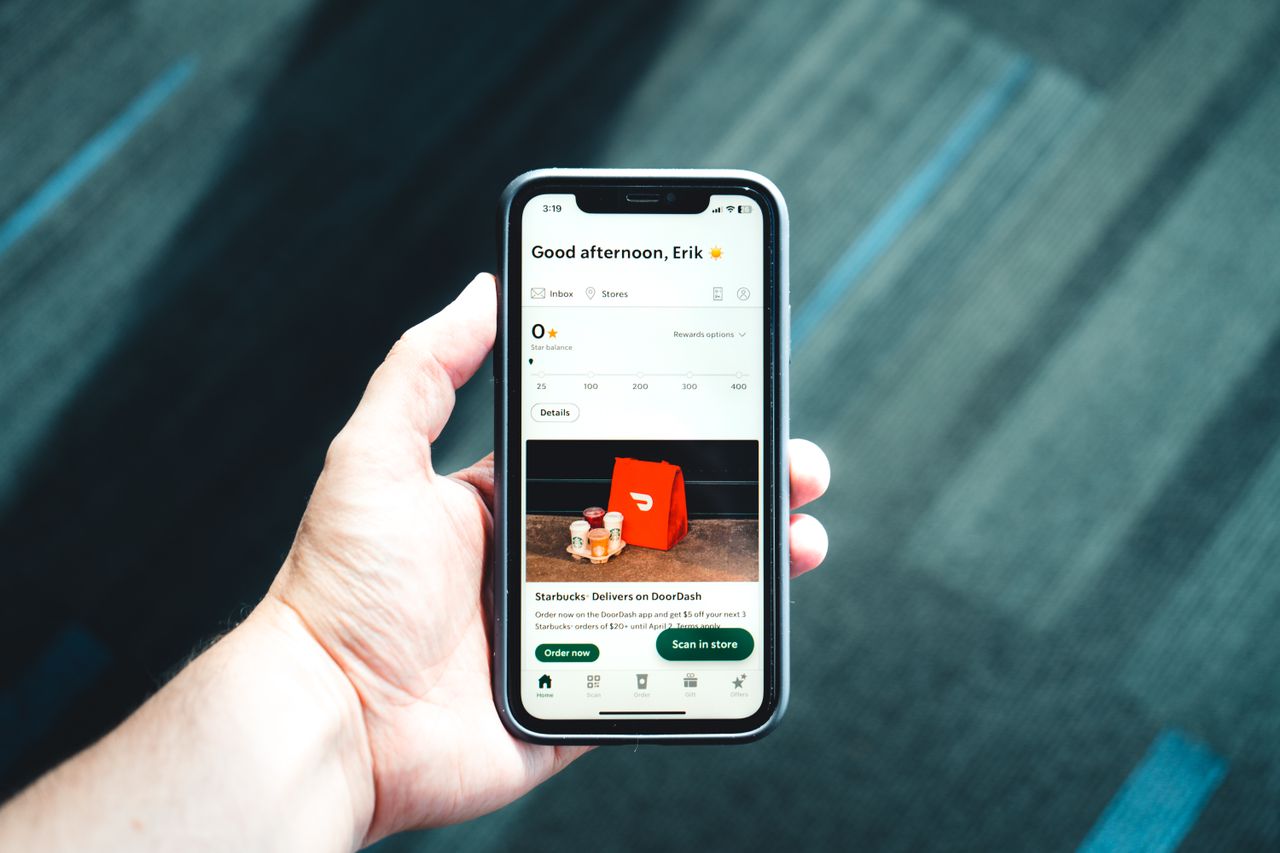 Close-up of a smartphone with a delivery app interface in a persons hand, emphasizing modern e-commerce.